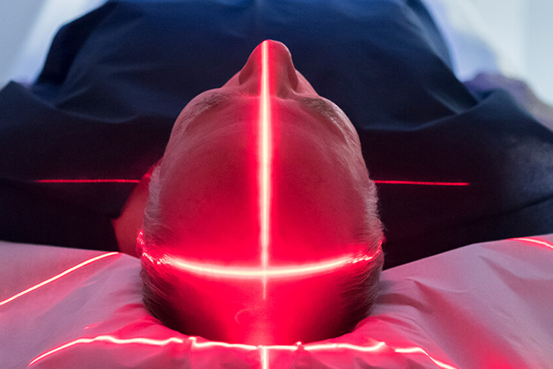 person in MRI with red lights scanning across head
