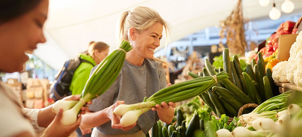A woman holding vegetables at a farmers market